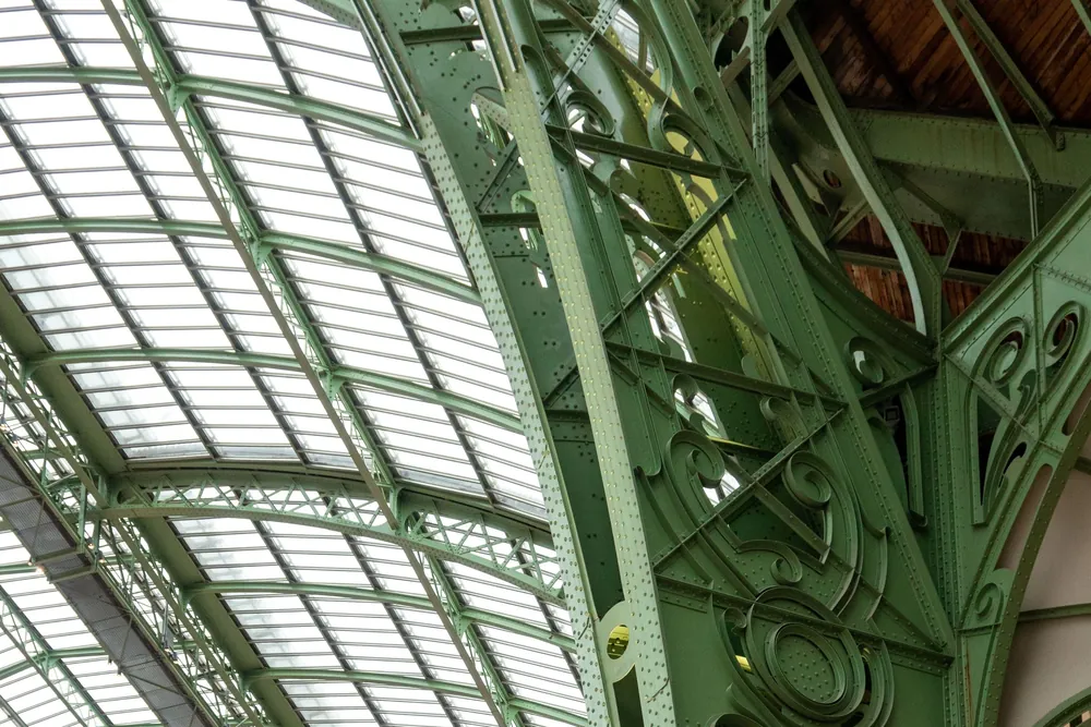 Verrière et charpente métallique vert réséda ornée de volutes, sous la nef du Grand Palais.