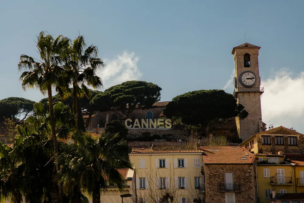 Le Suquet à Cannes avec ses grandes lettres CANNES, la tour de l'horloge et les pins parasols au-dessus des toits ocre.